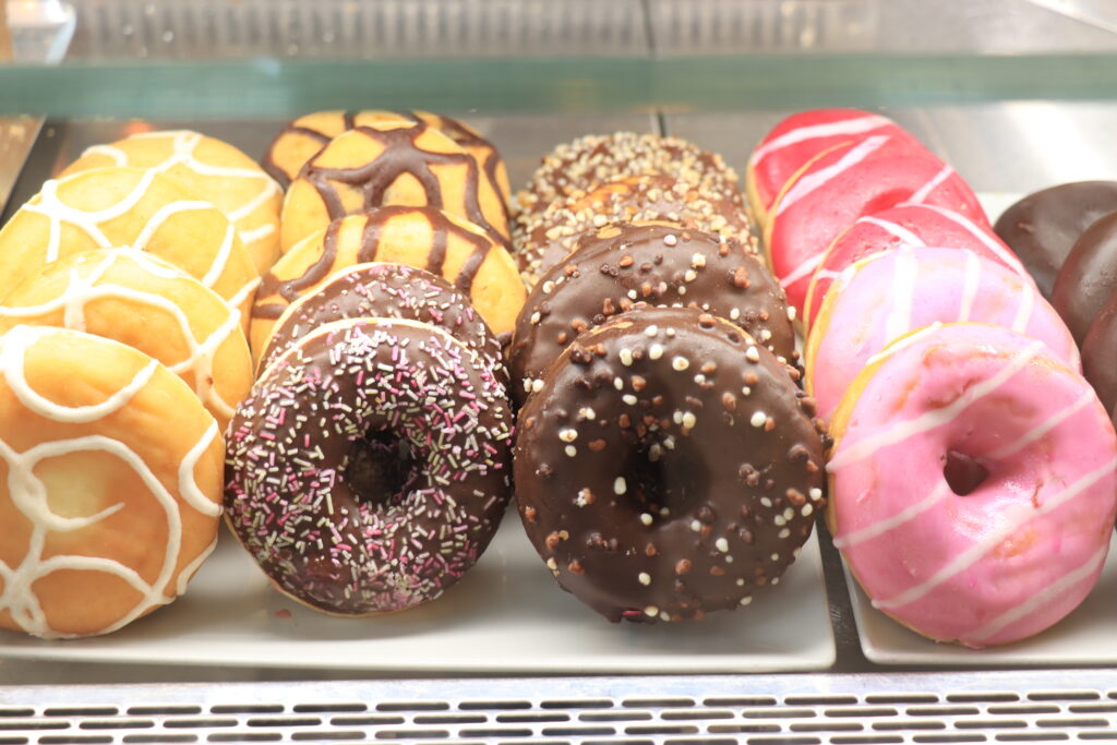 Various sorts of donuts in a shop window: pink icing and chocolate with sprinkles