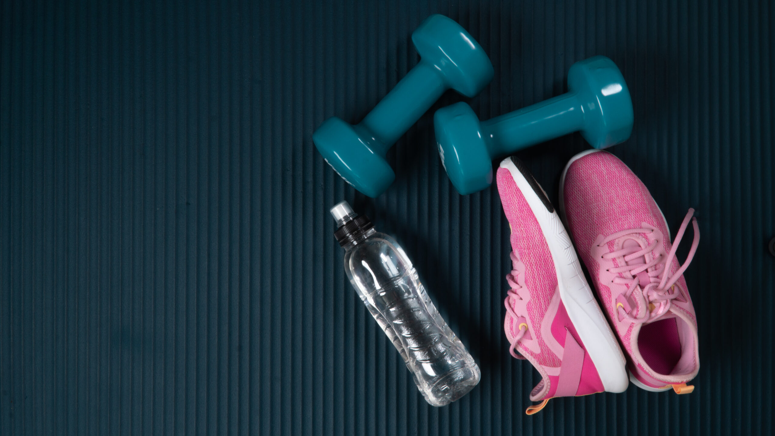 Sports gear on a mat including Sneakers, Water Bottle and Dumbells