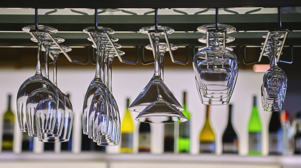 Glasses in the bar, restaurant interior. Clean glasses hang against the background of wine bottles.