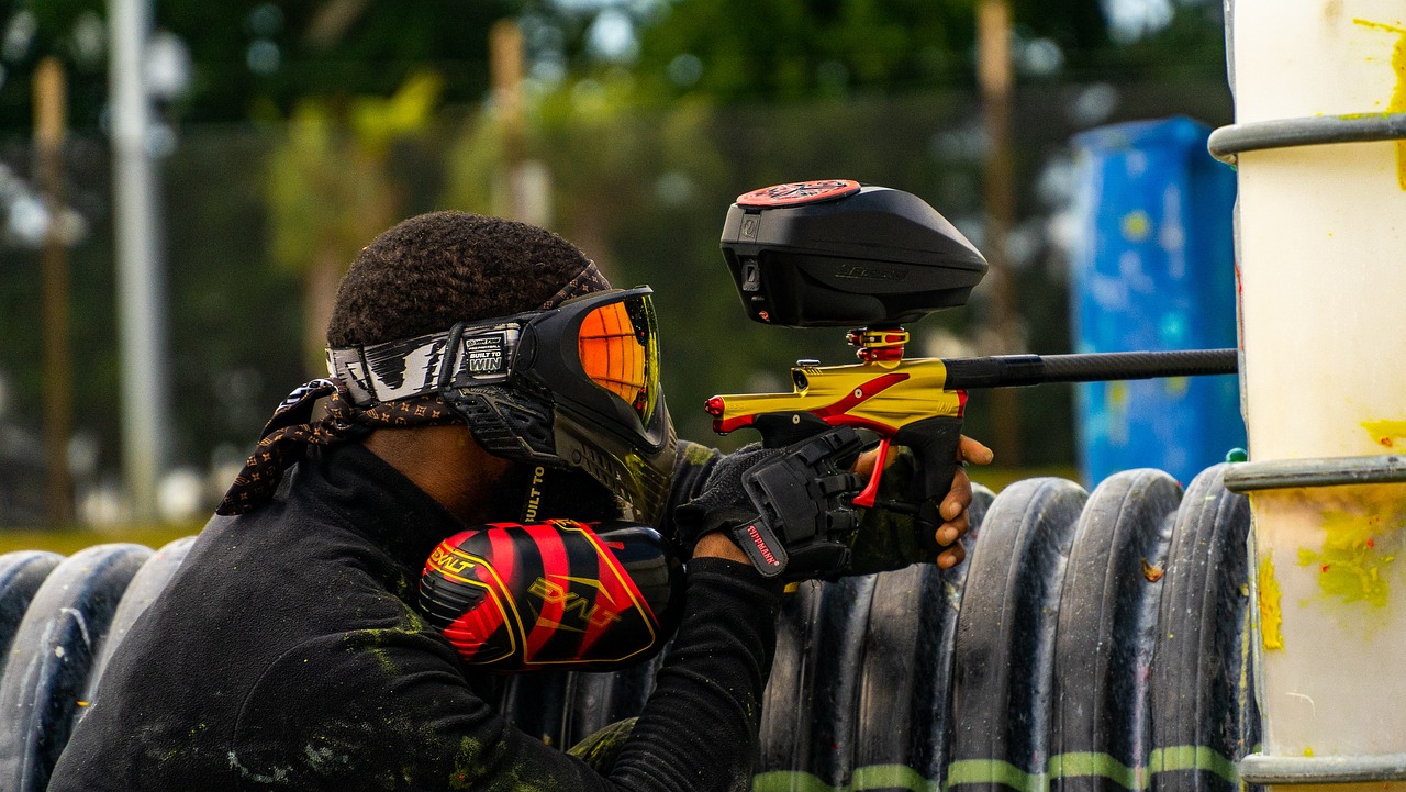 Person holding a paintball gun leaning on a barrel